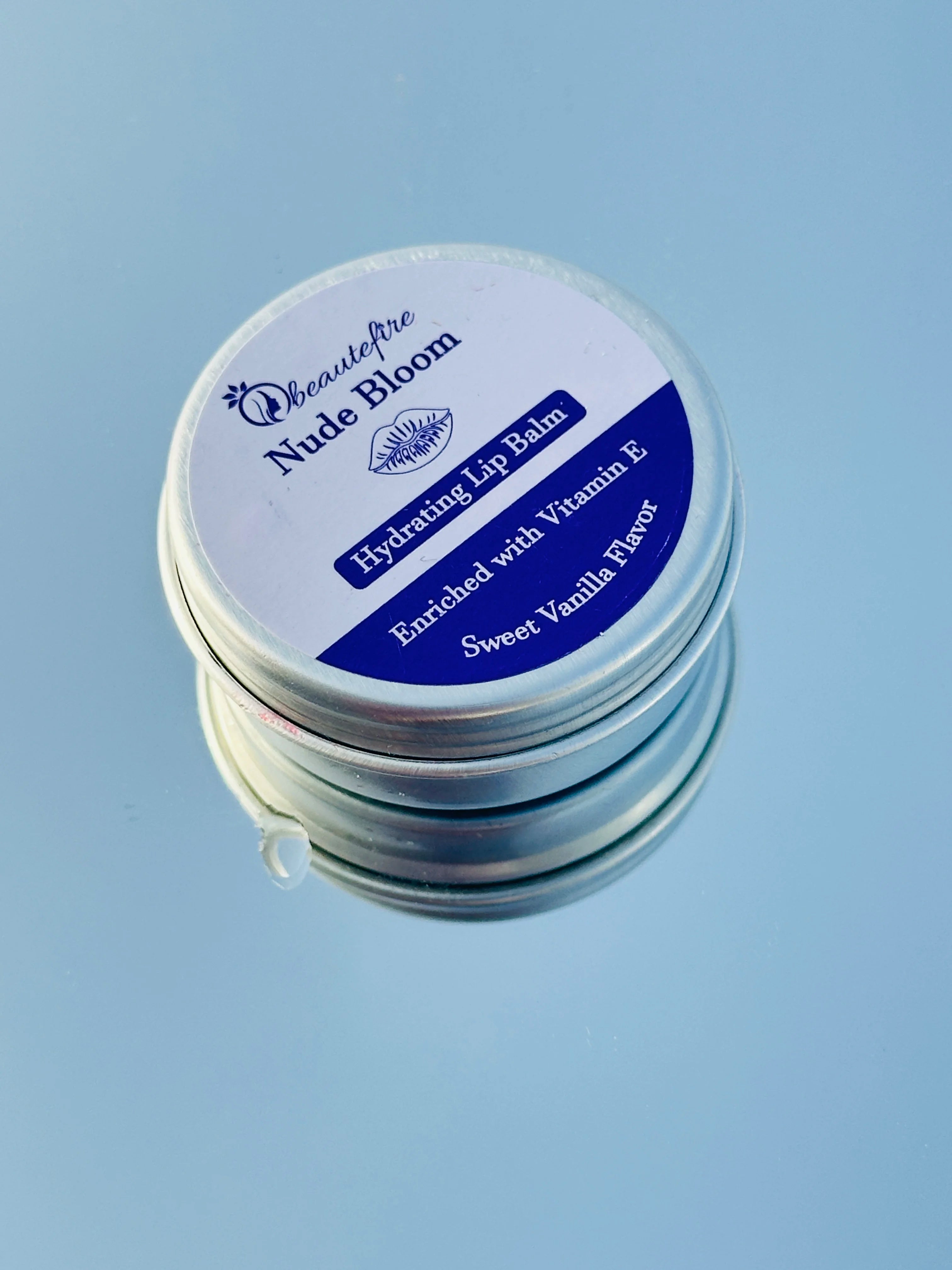 Beautefire Nude Bloom Lip Balm on sky with mirror ā elegant nude-tinted balm reflecting a soft, natural glow with deep nourishment.