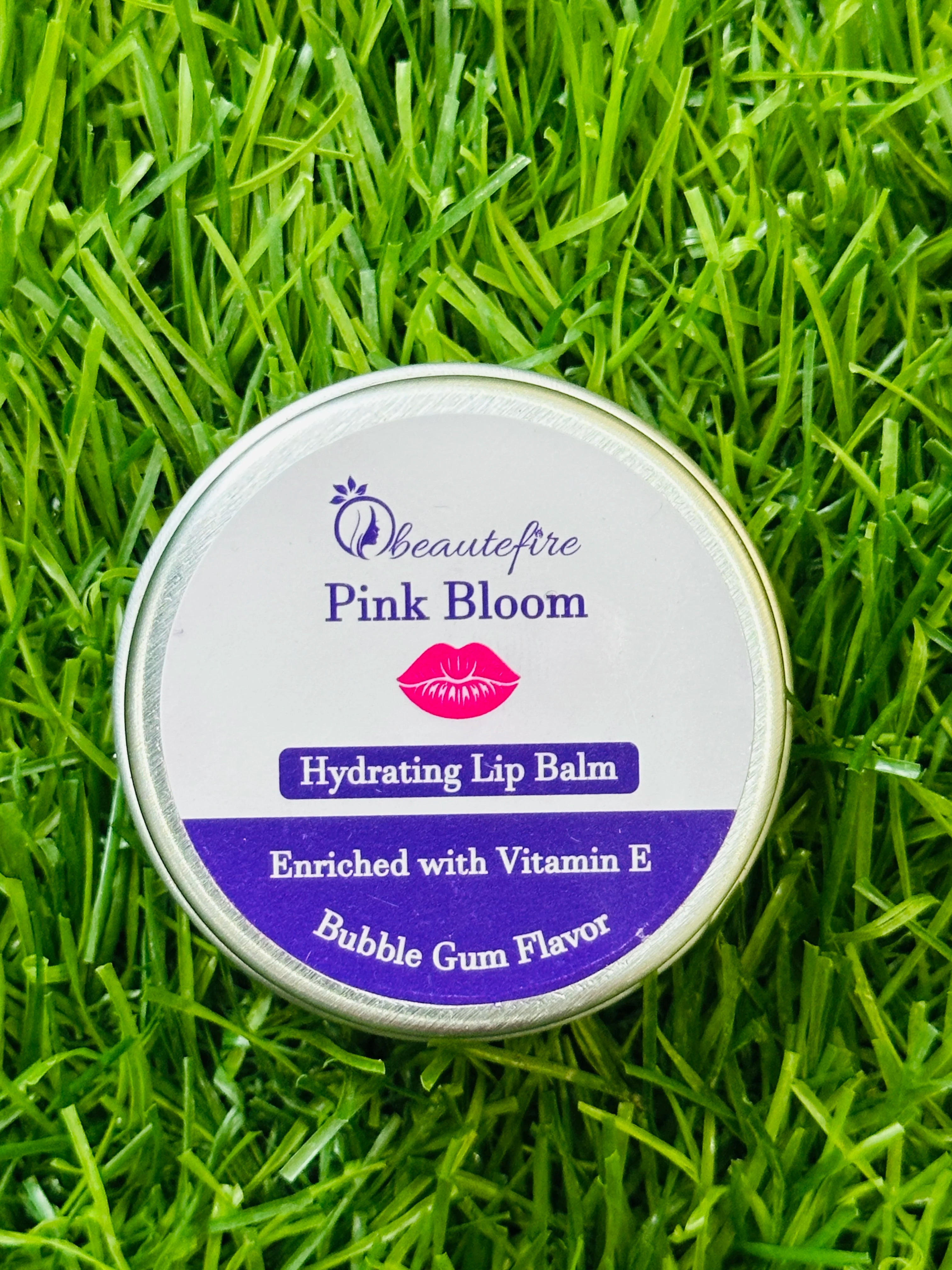 Beautefire Pink Bloom Lip Balm on grass ā natural beauty flat lay showing soft tint and nourishing formula.