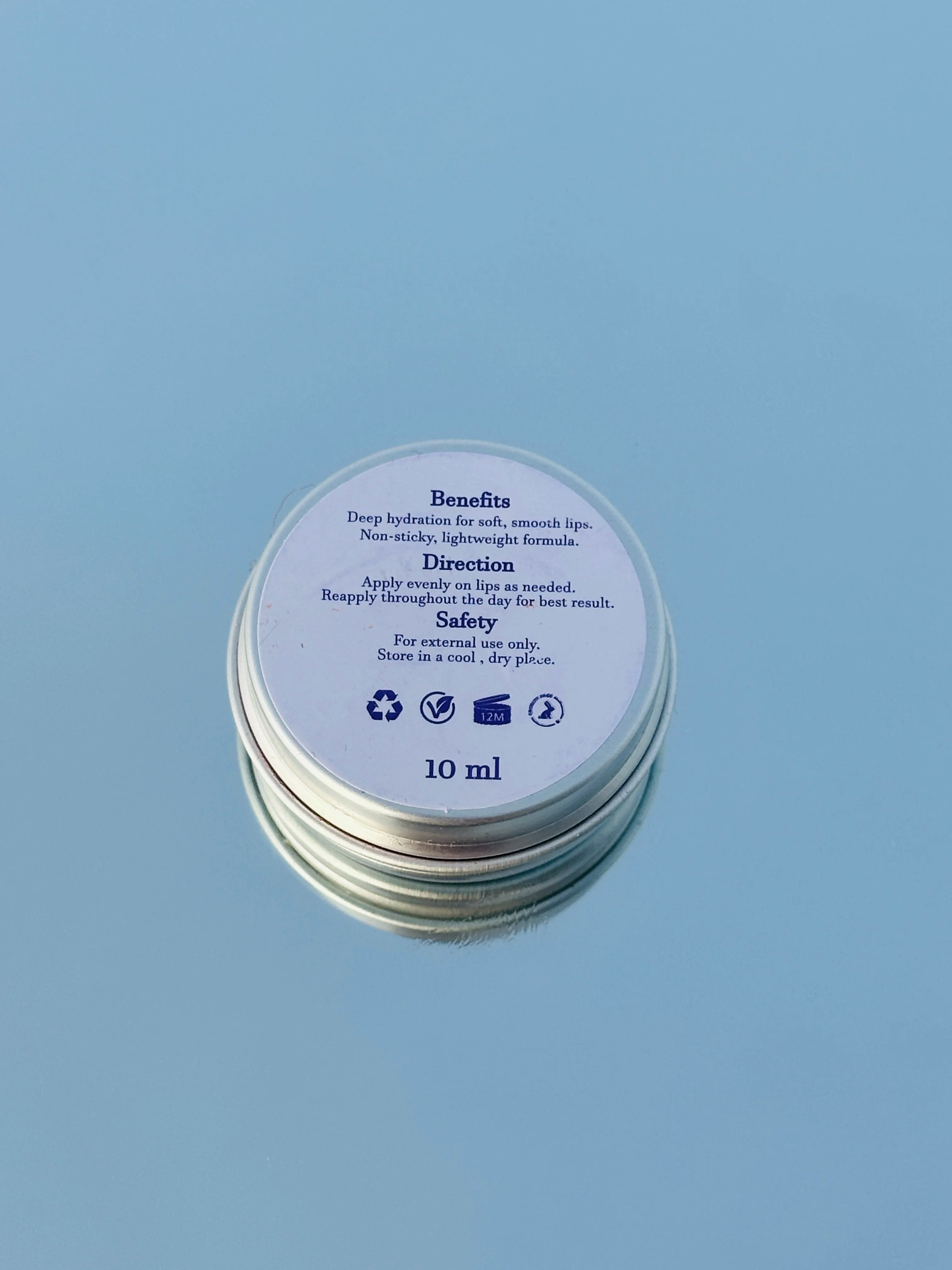 Beautefire Red Bloom Lip Balm back view on mirror and sky- repairing, moisturizing formula made for soft, healthy lips.