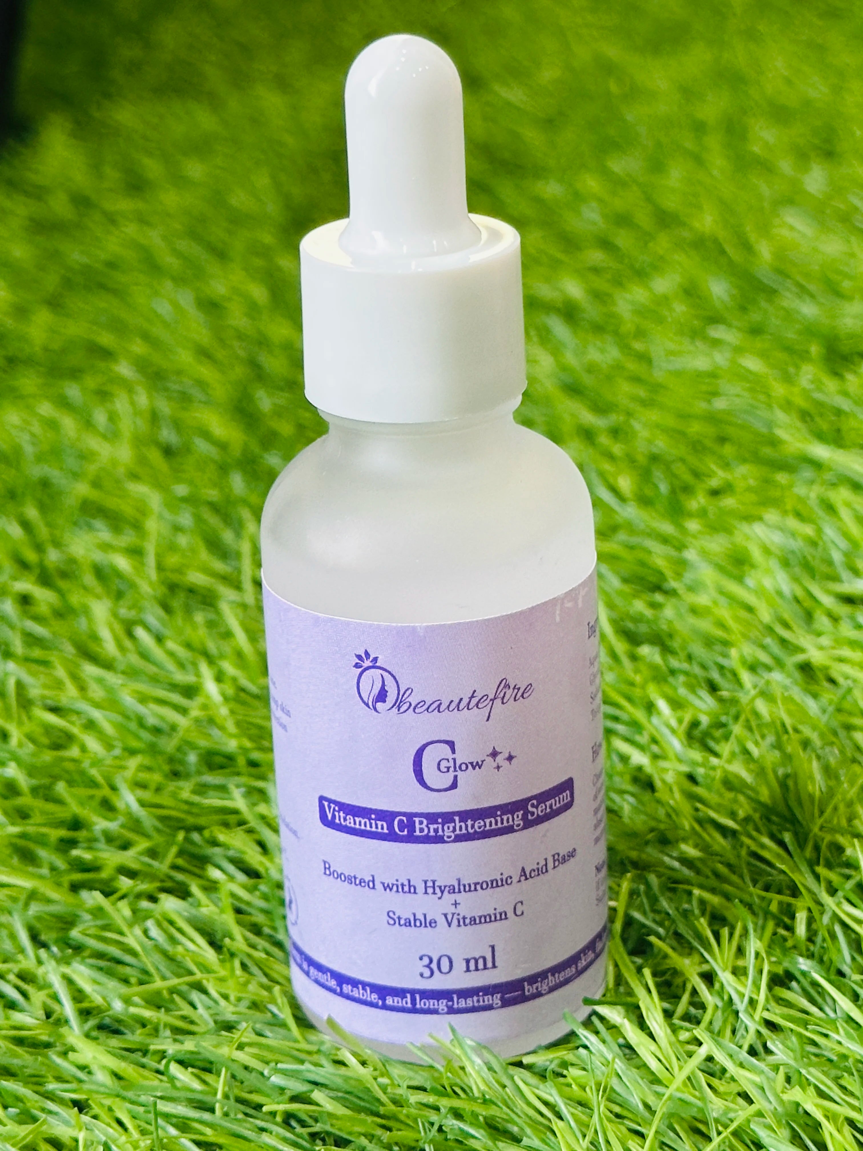 Beautefire C Glow Serum placed on grass — natural light capture of hydrating, glow-boosting Vitamin C serum.
