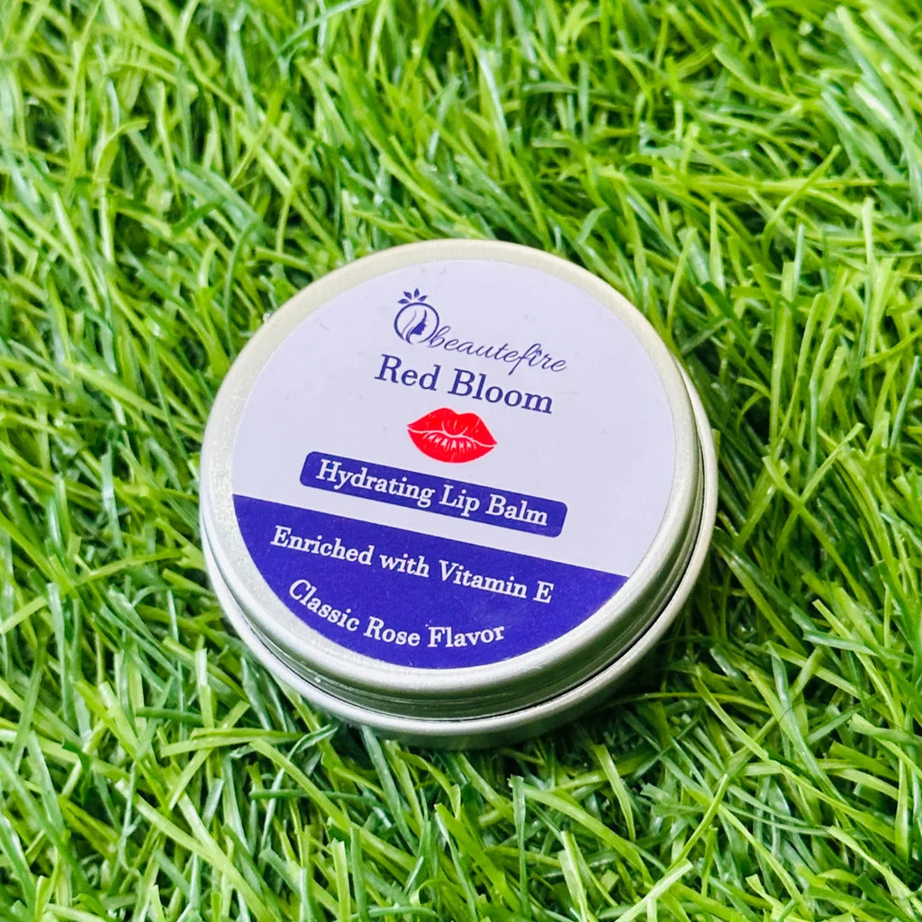Beautefire Red Bloom Lip Balm placed on grass — vibrant red nourishing balm captured in natural daylight.